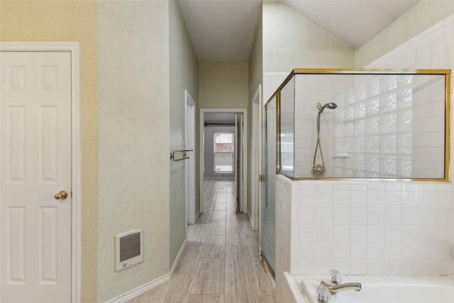 bathroom featuring heating unit, plus walk in shower, and wood-type flooring