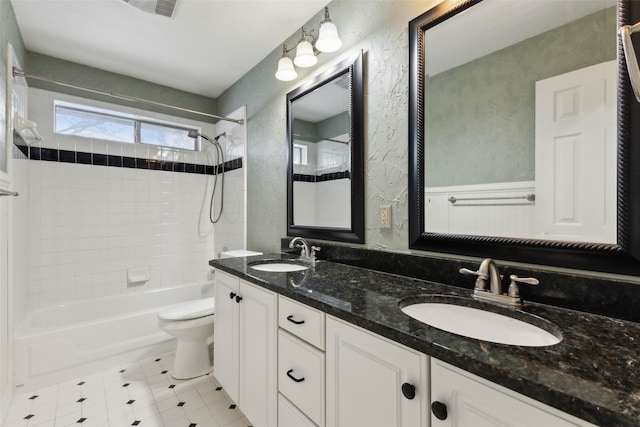 full bathroom featuring vanity, tiled shower / bath combo, and toilet