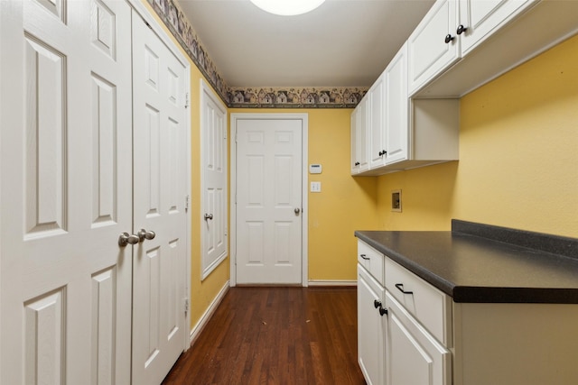 interior space featuring dark wood-type flooring, cabinets, and hookup for a washing machine