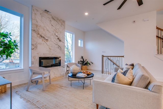 living room featuring ceiling fan, a premium fireplace, and light hardwood / wood-style flooring