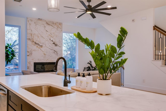 kitchen with plenty of natural light, ceiling fan, a premium fireplace, and sink