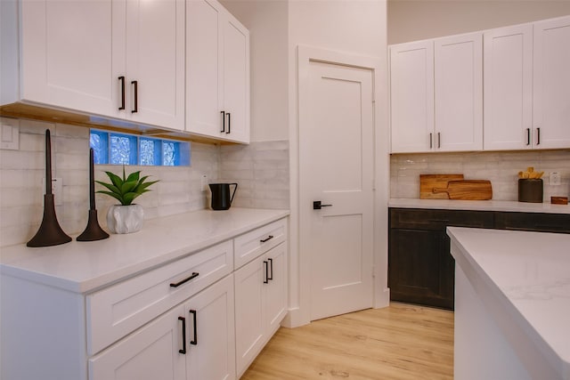 kitchen featuring backsplash, light stone counters, white cabinets, and light hardwood / wood-style floors