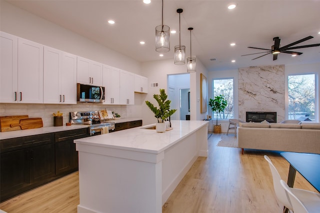 kitchen featuring a center island, white cabinets, ceiling fan, appliances with stainless steel finishes, and decorative light fixtures