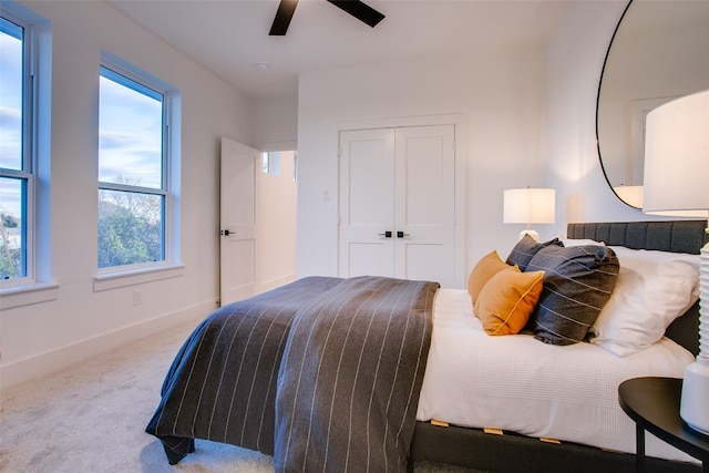 bedroom featuring ceiling fan, carpet floors, multiple windows, and a closet