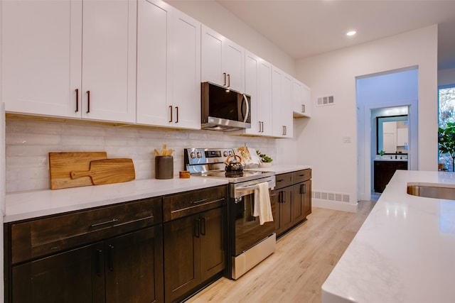 kitchen with stainless steel appliances, white cabinetry, light hardwood / wood-style floors, and sink