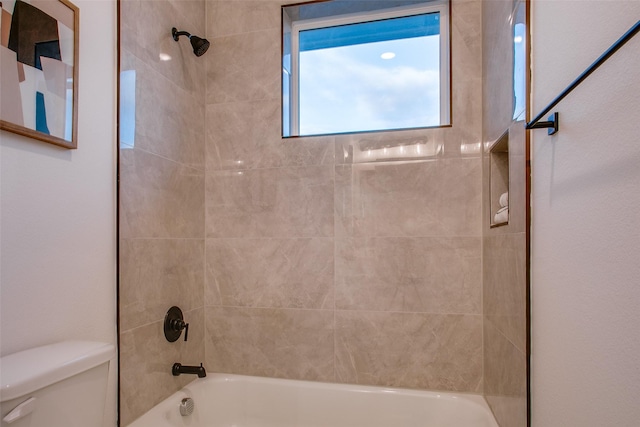 bathroom featuring toilet and tiled shower / bath