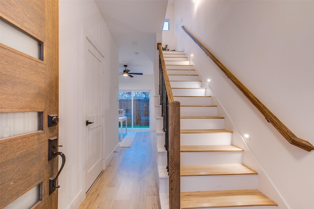 stairway featuring ceiling fan and wood-type flooring