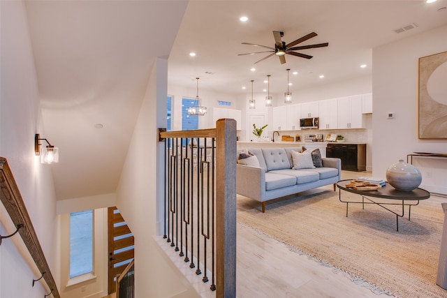 living room featuring sink, ceiling fan with notable chandelier, and light wood-type flooring