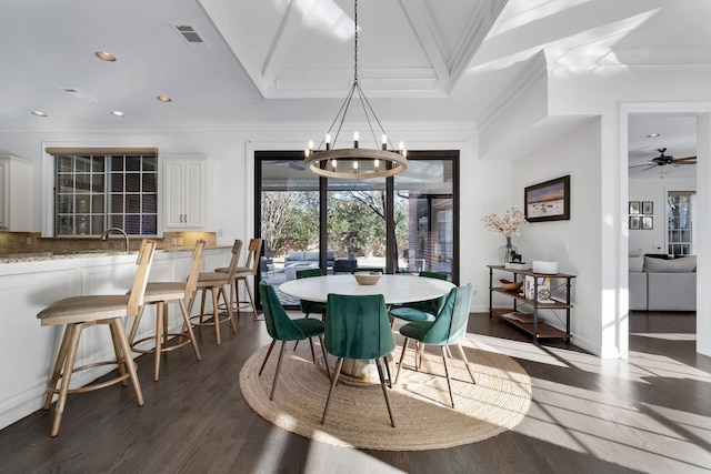 dining space featuring dark hardwood / wood-style floors, crown molding, vaulted ceiling, a tray ceiling, and ceiling fan with notable chandelier