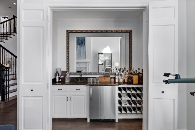 bar featuring dark wood-type flooring, white cabinets, crown molding, dark stone countertops, and fridge