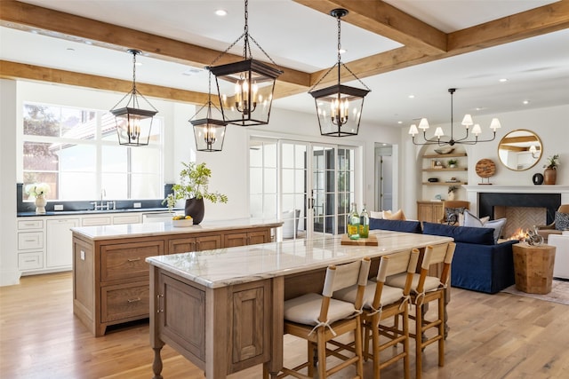 kitchen with pendant lighting, a spacious island, light stone countertops, light hardwood / wood-style floors, and a kitchen bar