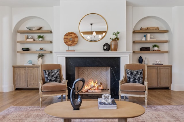 living area with built in shelves, light wood-type flooring, and a chandelier