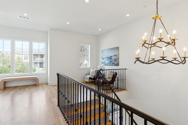 hall with light hardwood / wood-style flooring and a notable chandelier