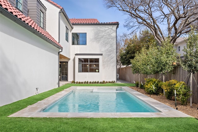 back of property with a yard and a fenced in pool