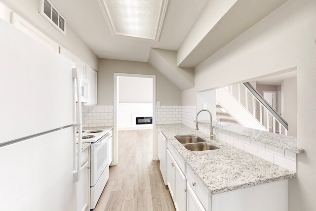 kitchen featuring white cabinetry, sink, light stone countertops, white appliances, and decorative backsplash