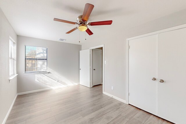 unfurnished bedroom with ceiling fan, a closet, and light wood-type flooring