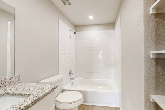 full bathroom with hardwood / wood-style floors, vanity, toilet, and tiled shower / bath