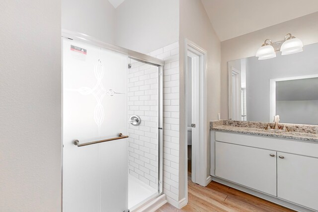 bathroom with vanity, wood-type flooring, lofted ceiling, and a shower with shower door