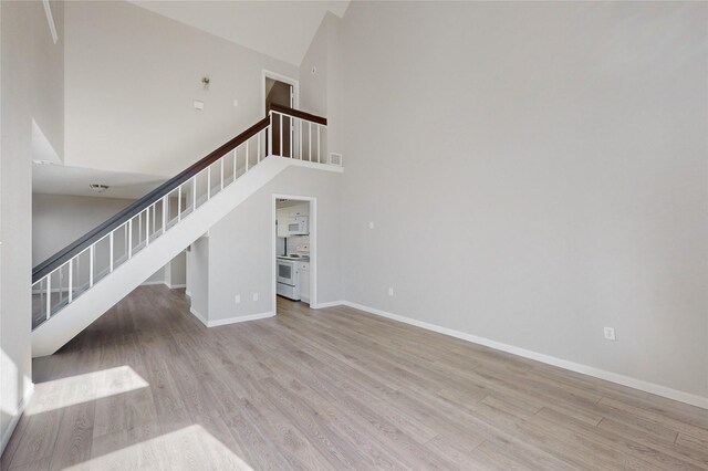 unfurnished living room featuring light wood-type flooring and a high ceiling