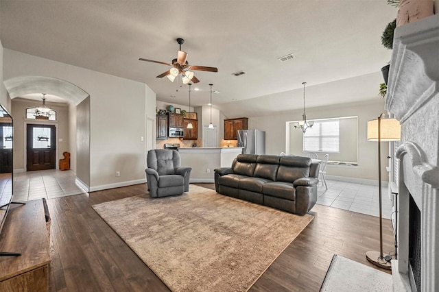 living room featuring ceiling fan with notable chandelier and dark wood-type flooring