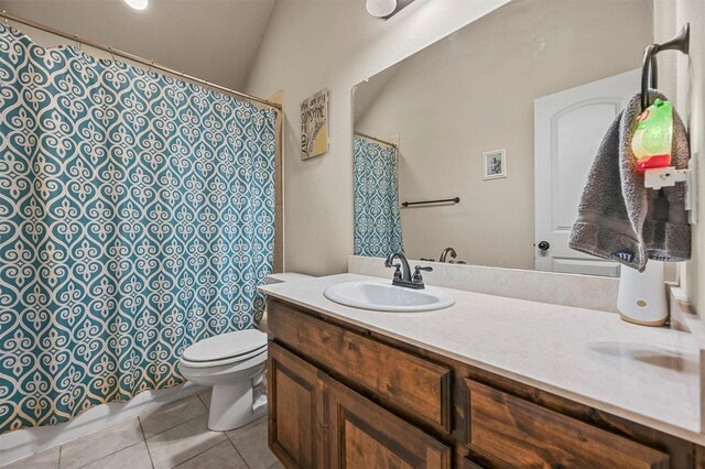 bathroom with tile patterned flooring, vanity, lofted ceiling, and toilet