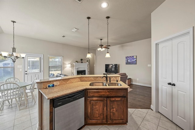 kitchen featuring sink, stainless steel dishwasher, an island with sink, light tile patterned floors, and ceiling fan with notable chandelier