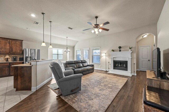 living room featuring ceiling fan with notable chandelier, dark hardwood / wood-style floors, and lofted ceiling