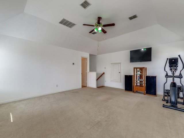 unfurnished living room featuring a raised ceiling, vaulted ceiling, light colored carpet, and ceiling fan