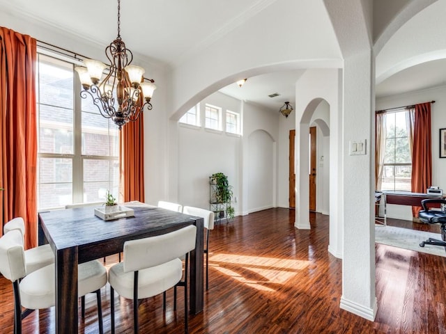 dining area featuring crown molding, dark hardwood / wood-style flooring, and an inviting chandelier