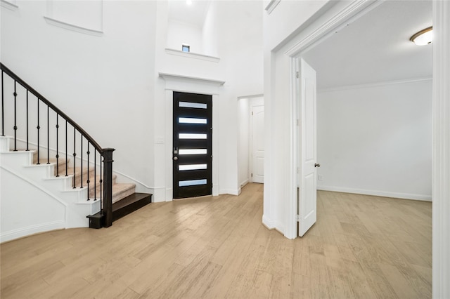 foyer entrance featuring crown molding and light hardwood / wood-style floors