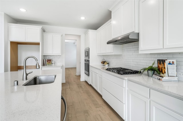 kitchen with exhaust hood, sink, light stone countertops, white cabinetry, and stainless steel appliances