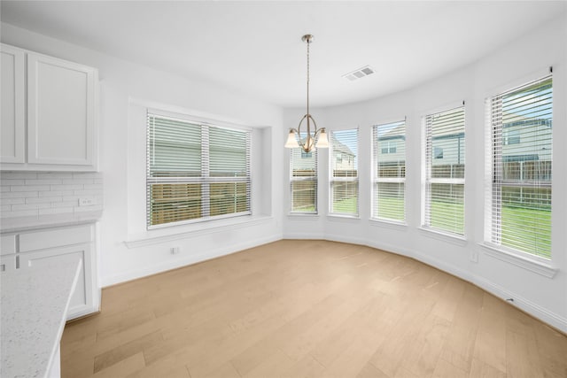 unfurnished dining area featuring light wood-type flooring and an inviting chandelier