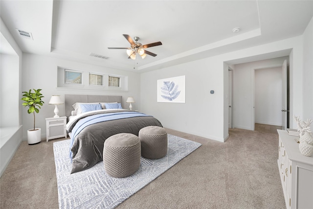 carpeted bedroom featuring a tray ceiling and ceiling fan