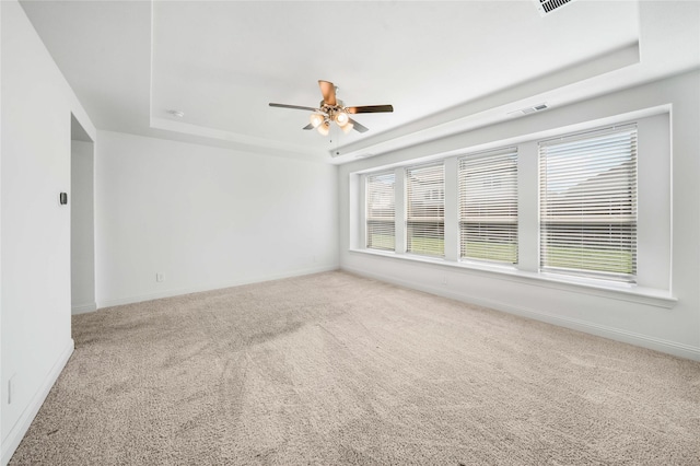 carpeted spare room with ceiling fan and a tray ceiling