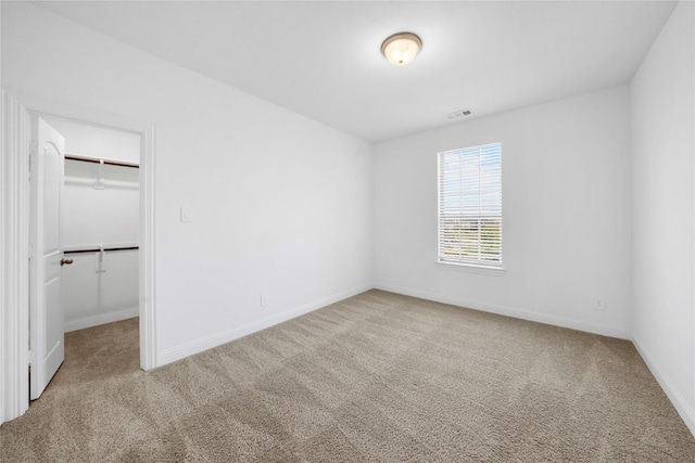 unfurnished bedroom featuring carpet floors, a spacious closet, and a closet