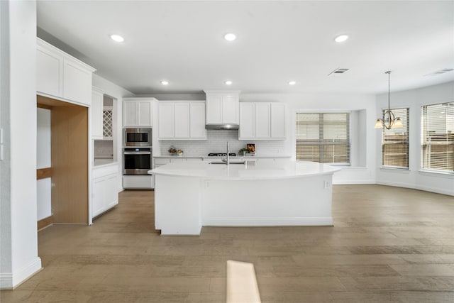 kitchen featuring an island with sink, light hardwood / wood-style flooring, white cabinets, and stainless steel appliances