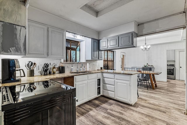 kitchen featuring sink, hanging light fixtures, kitchen peninsula, hardwood / wood-style floors, and range