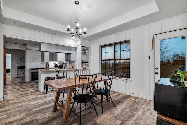 dining area with a tray ceiling, an inviting chandelier, and dark wood-type flooring