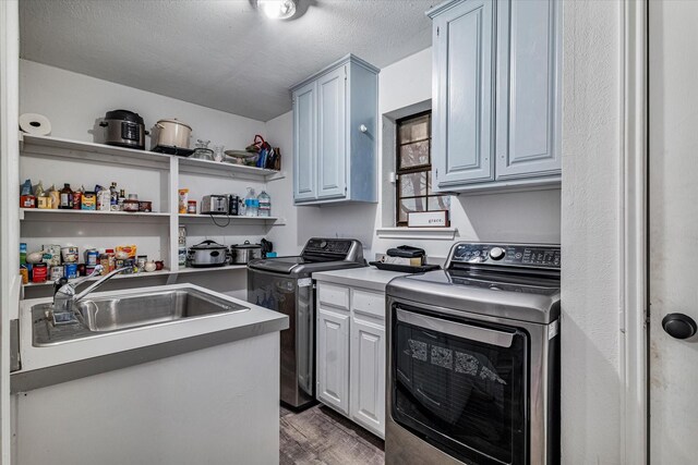 washroom with cabinets, a textured ceiling, separate washer and dryer, and sink