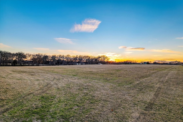 yard at dusk featuring a rural view