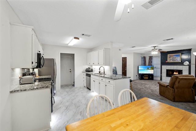 kitchen with dishwasher, decorative backsplash, white cabinetry, dark stone countertops, and sink