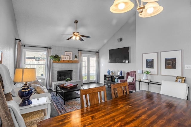 living room featuring ceiling fan, high vaulted ceiling, a brick fireplace, and french doors