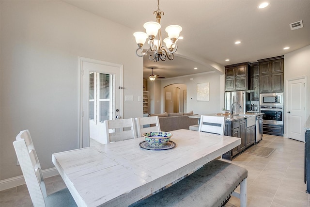 dining space with light tile patterned flooring, ceiling fan with notable chandelier, and sink