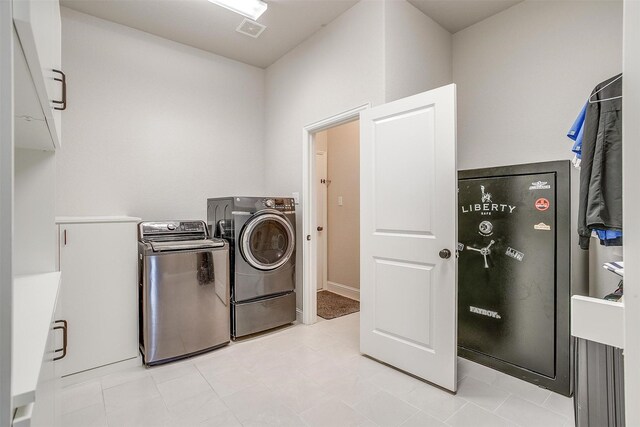 laundry room with separate washer and dryer and cabinets