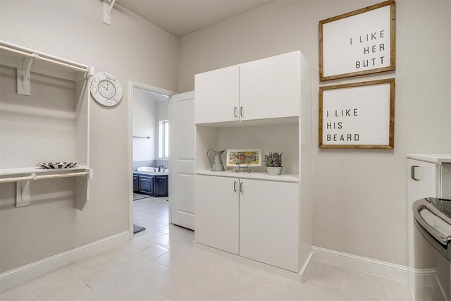 laundry area with cabinets, light tile patterned floors, and sink