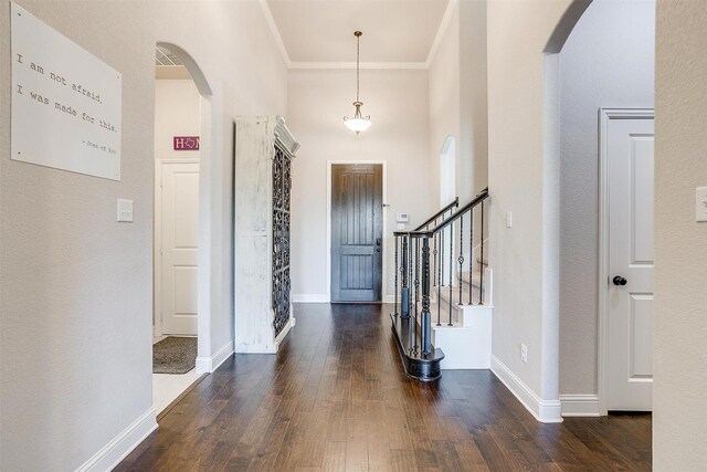 foyer entrance featuring dark hardwood / wood-style flooring, ornamental molding, and a high ceiling