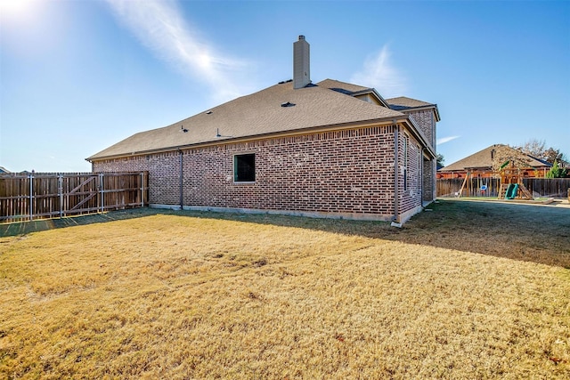 back of house with a playground and a lawn