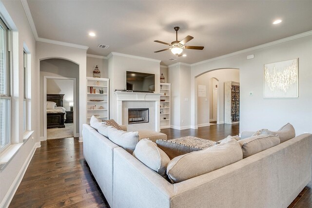 living room with ceiling fan, dark hardwood / wood-style flooring, ornamental molding, and built in shelves