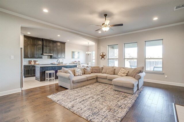 living room featuring ceiling fan with notable chandelier, dark hardwood / wood-style floors, and ornamental molding