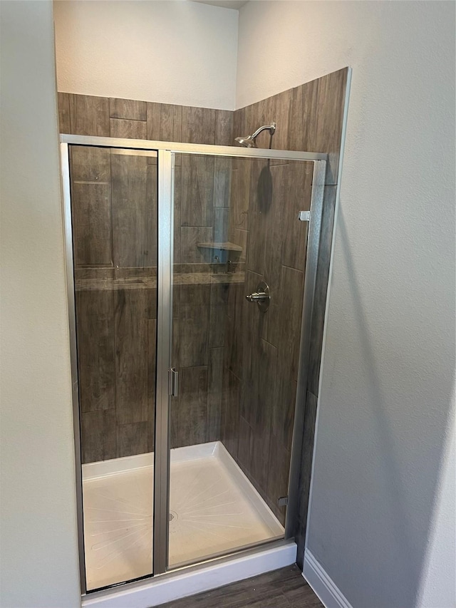 bathroom featuring a stall shower, baseboards, and wood finished floors